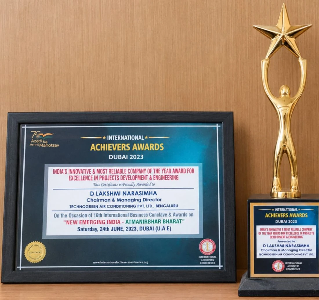 A framed International Achievers Awards Dubai 2023 certificate beside its gold star trophy. The certificate reads India's Innovative and Most Reliable Company of the Year Award for Excellence in Projects Development and Engineering, awarded to D Lakshmi Narasimha, Chairman and Managing Director, Technogreen Air Conditioning Pvt. Ltd., Bengaluru, on the occasion of the 16th International Business Conclave and Awards on New Emerging India — Atmanirbhar Bharat, Saturday 24th June 2023, Dubai, U.A.E.