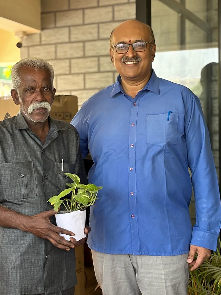 A member of the site crew and a colleague holding the potted plant given at a birthday celebration.