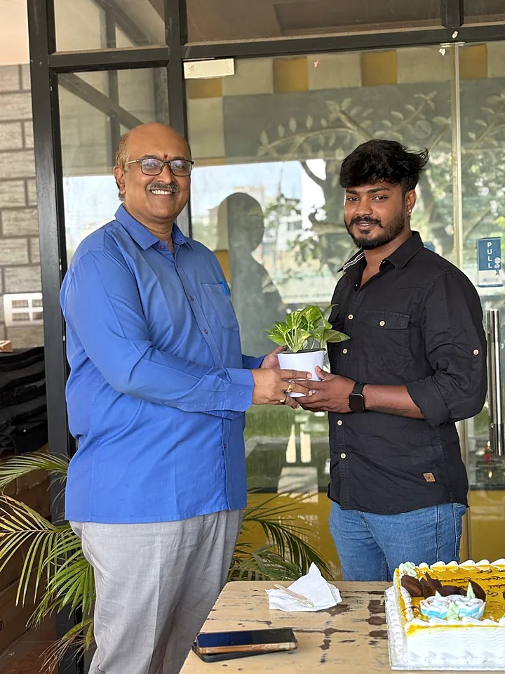 A colleague being handed a potted plant at the office door.