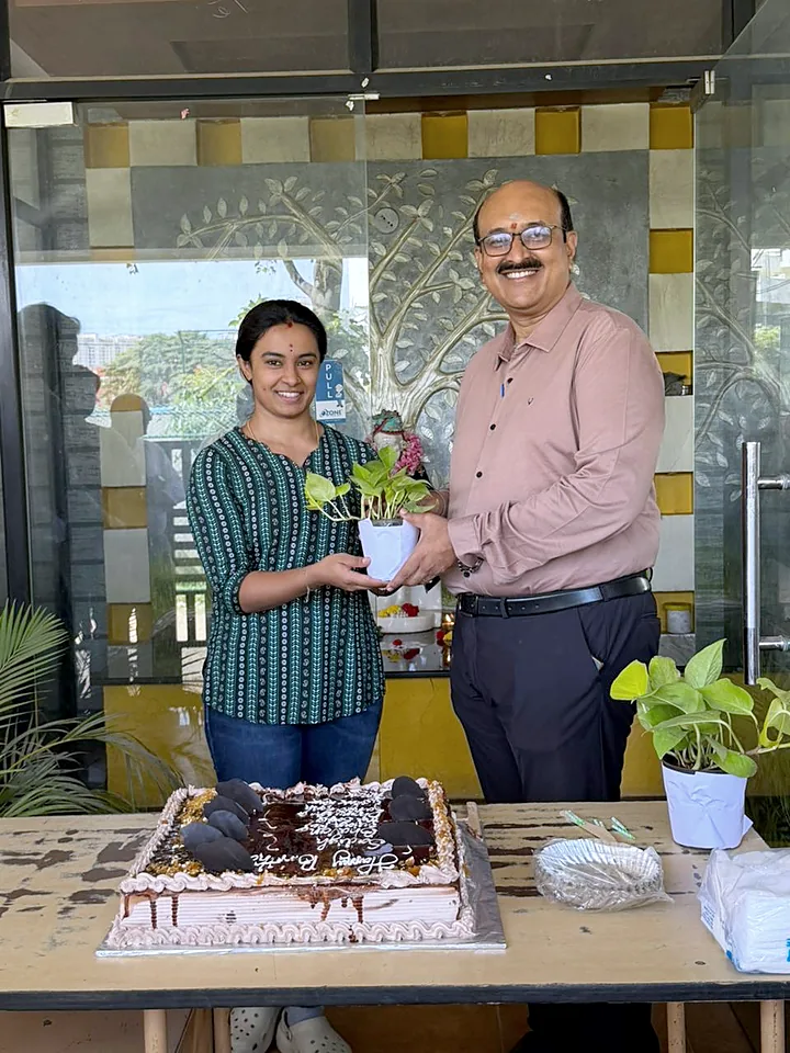 A colleague receiving a potted plant beside the glass doors of the office.