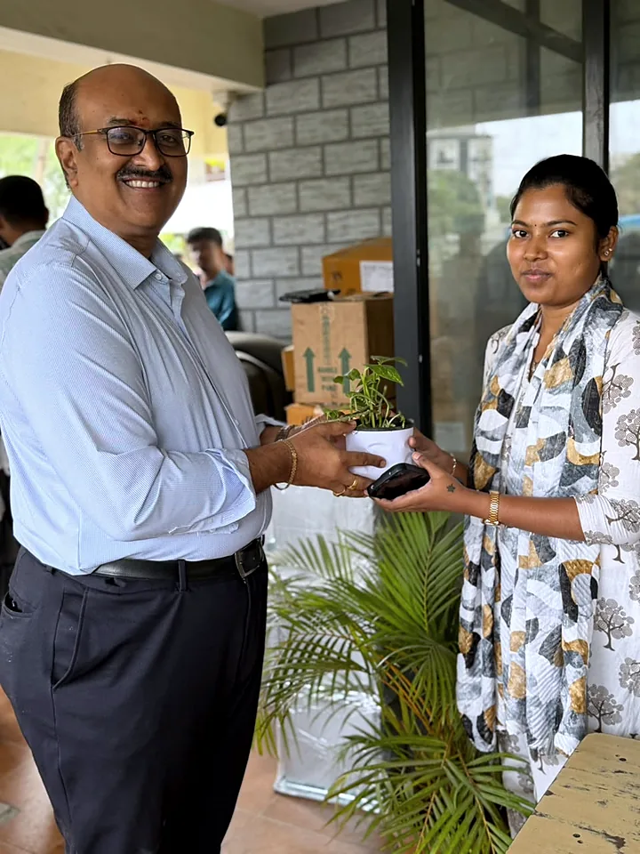 A colleague receiving a potted plant on the office porch.