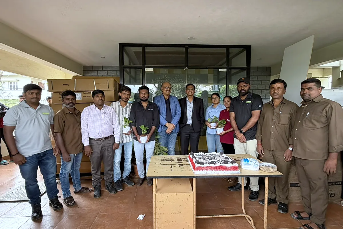 The team lined up behind a birthday cake on the office porch, office staff and site crew together.