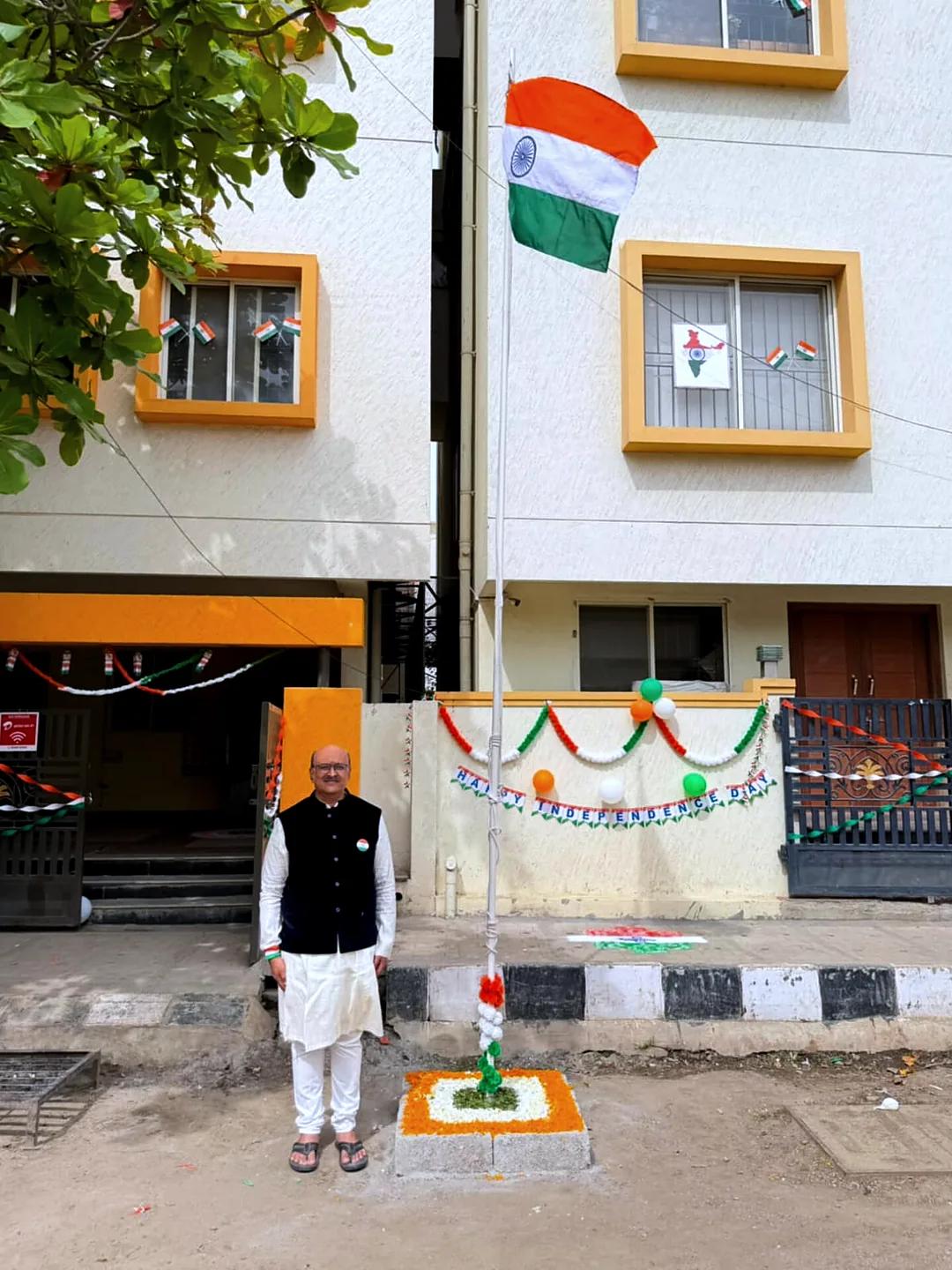 The national flag flying from the pole outside the Technogreen office, a colleague standing at its base beside the decorated entrance.
