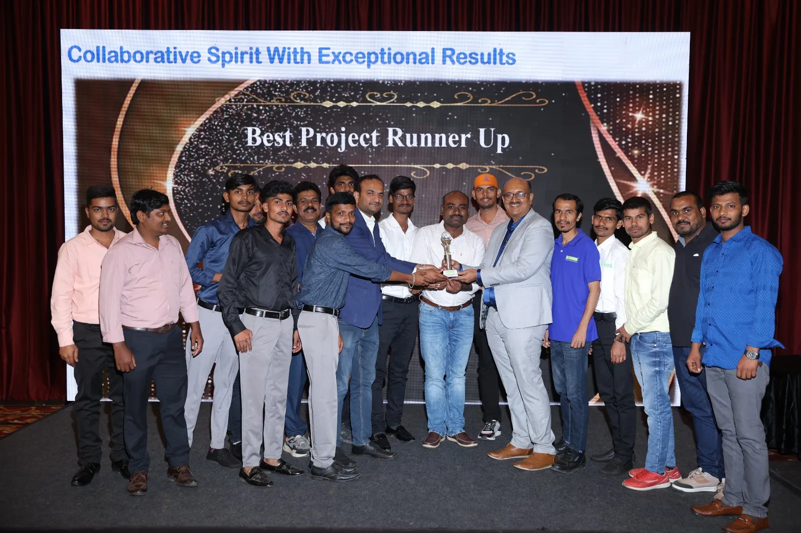 A project team on stage with a trophy under a screen reading Best Project Runner Up.