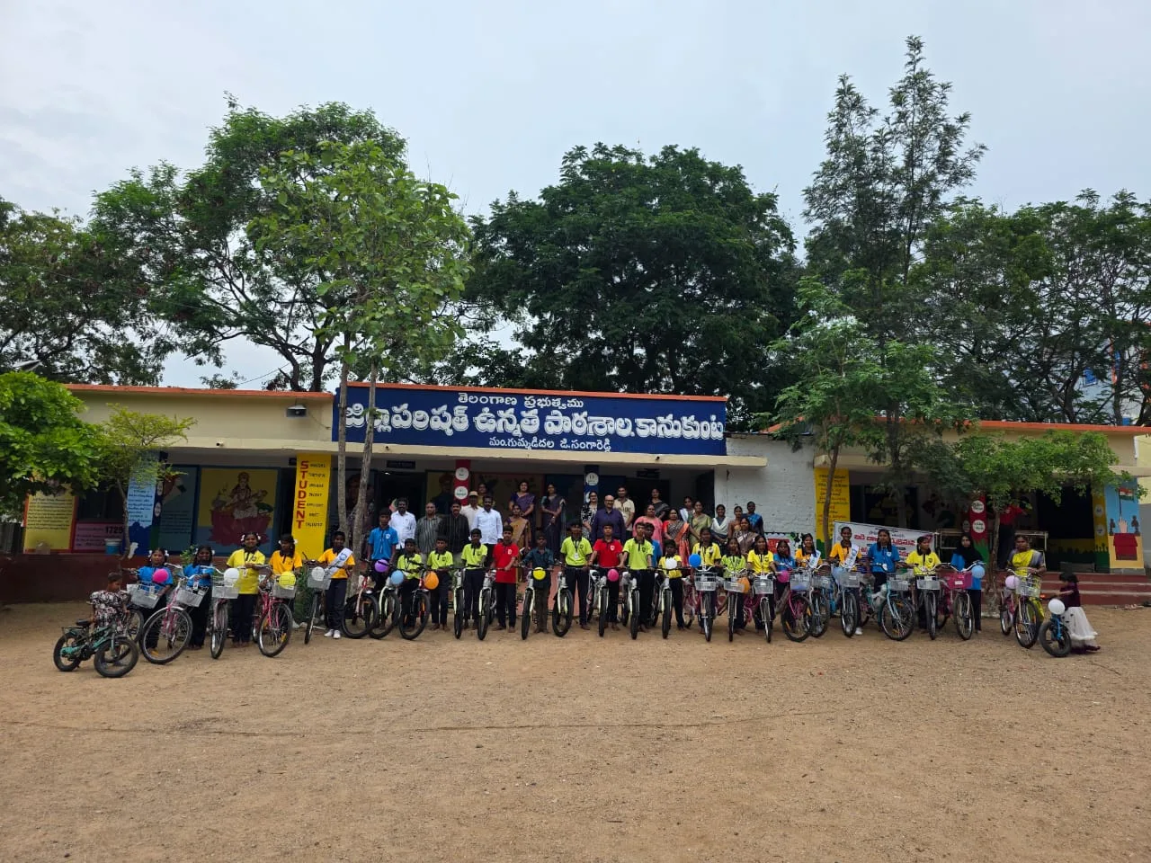 School children standing with a long row of new bicycles on the school ground.