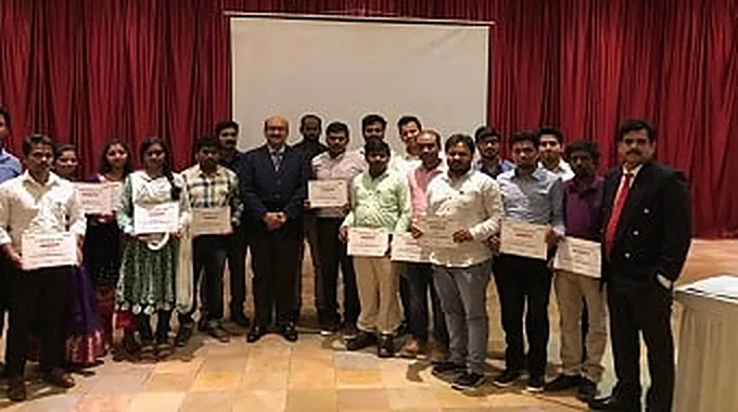 Trainees on stage with their certificates beside the presenter.