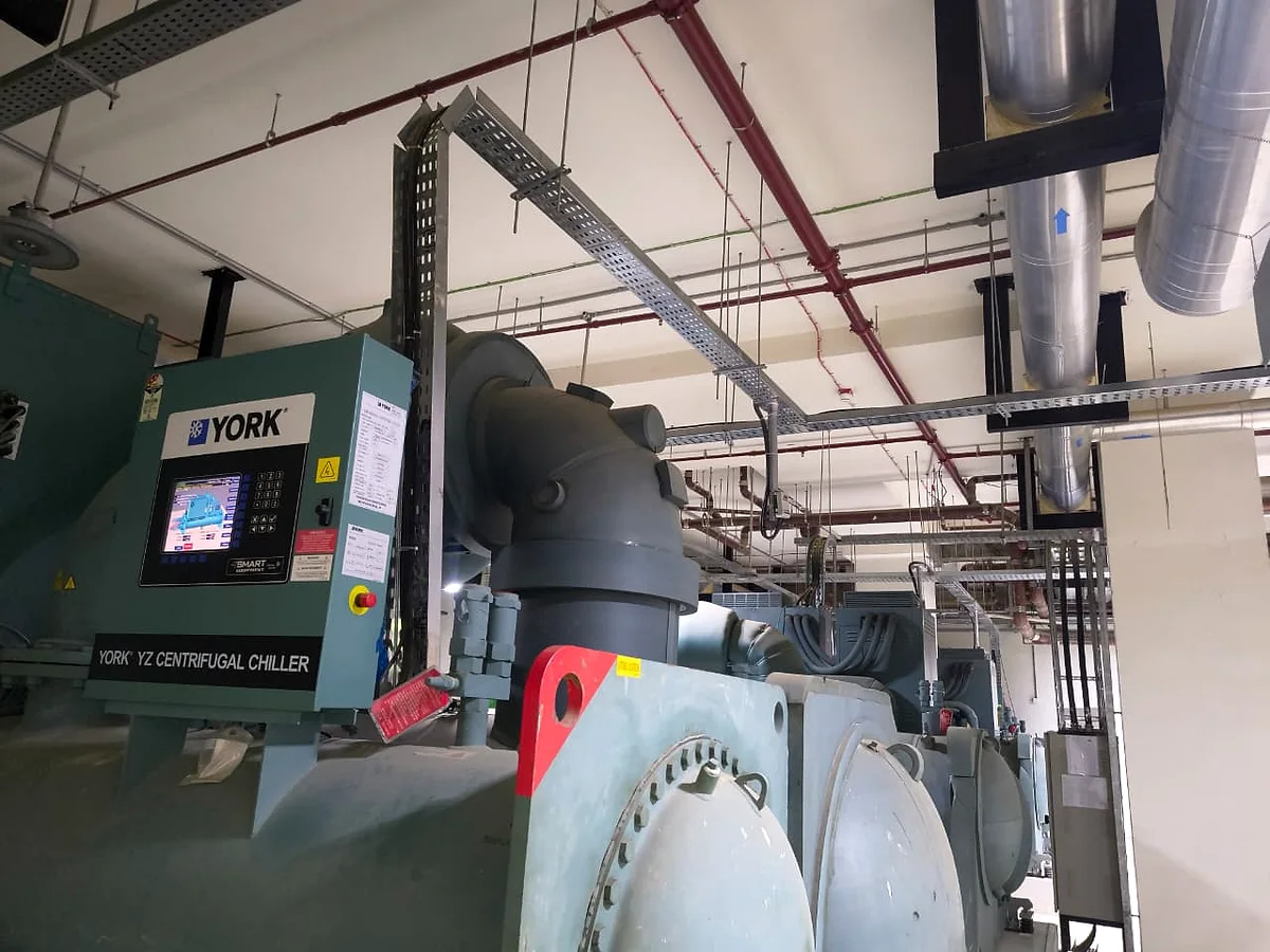 A York centrifugal chiller with its control panel lit, the machine's suction elbow and flanged head in the foreground.