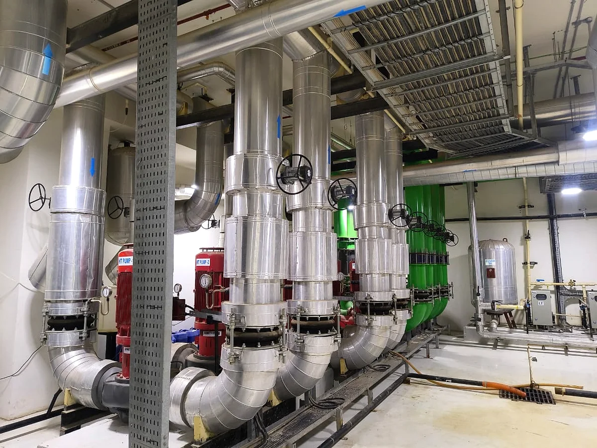 Insulated chilled-water headers in silver lagging, turning through butterfly valves above the chillers.